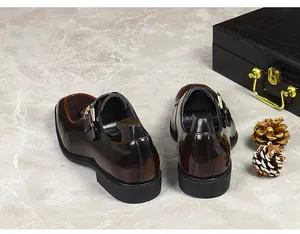 Detail of dark brown glossy leather monk shoe with gold buckle and rubber sole