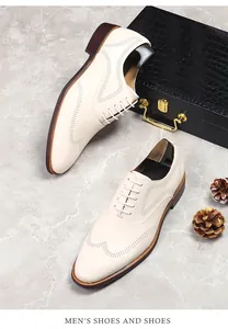 Detail view of cream white leather wingtip brogue shoes on marble surface with wooden trees
