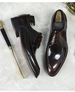 Detail of dark brown shiny leather derby shoes with classic laces and moccasin stitching