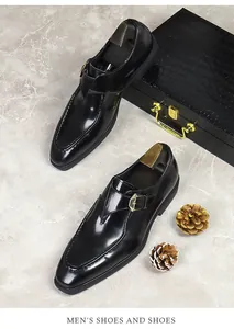 Close-up of black patent leather monk strap shoe with gold buckle on marble surface