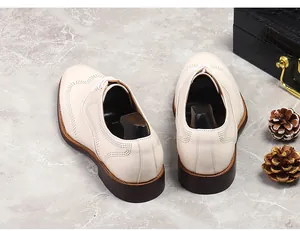 Detailed view of beige leather brogue shoes with decorative perforation on a marble surface