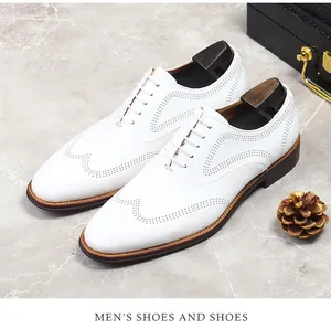 Detail of white leather Brogue shoes with wingtip carving and brown sole on marble
