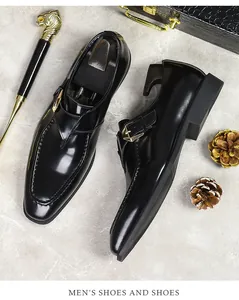 Detail of black patent leather monk strap shoe with gold buckle on marble surface