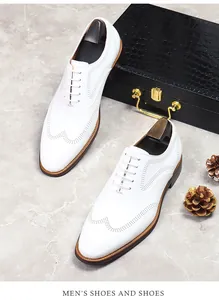 Detail shot of white leather brogue shoes with wingtip perforations on marble background