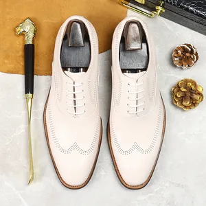 Beige leather brogue oxfords with classic wingtip details and white laces in a premium setting