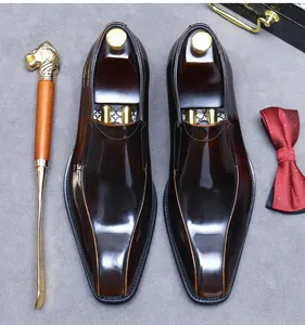 Vista dall'alto di scarpe eleganti marroni con calzante in ottone e papillon rosso