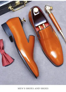 Gros plan sur les mocassins en cuir brillant marron-orange avec doublure rouge et accessoires
