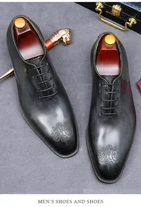 Detail van zwarte lederen oxford schoenen met elegant reliëf embleem op de neus
