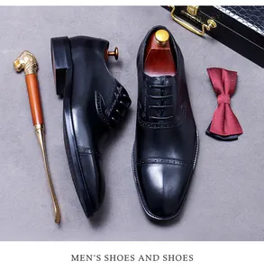 Detail of black leather cap-toe dress shoes with brogue patterns and luxury accessories