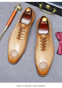 Detail van tan lederen oxford schoenen met laserpatronen en houten schoenspanners erop