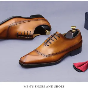 Nahaufnahme brauner Oxford-Schuhe aus Leder mit Brogue-Verzierung und einer roten Fliege