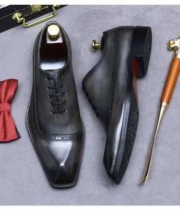 Detail von dunkelgrauen Leder-Brogue-Schuhen mit klassischen Lochmustern und Premium-Patina