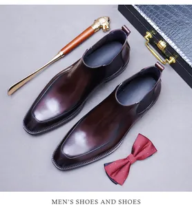 Detail von weinroten Chelsea-Boots aus Leder mit Hochglanz-Finish und Löwenkopf-Schuhanzieher