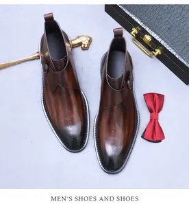 Close-up of brown leather boots with monk straps and artistic letter engraving details