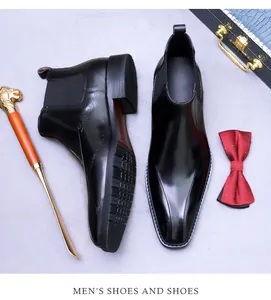 Détail de bottines Chelsea en cuir noir avec embossage latéral et chausse-pied doré