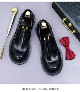 Glanzende zwarte herenloafers van leer gepresenteerd met luxe zakelijke accessoires