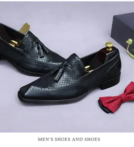 Dettaglio di mocassini in pelle nera con nappe, trafori brogue e tendiscarpe di lusso