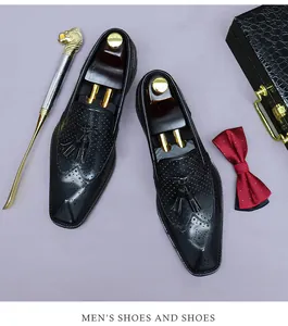 Primo piano di mocassini in pelle nera con trafori brogue e doppie nappe sulle scarpe