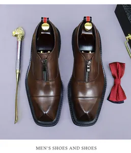 Macro view of brown leather dress shoes featuring a central metal zipper and square toe