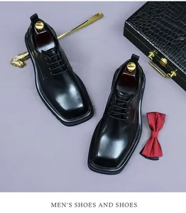 Top view of black leather square-toe men's dress shoes with professional business accessories