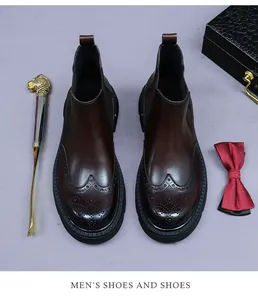 Close-up of brown leather Chelsea boots featuring classic brogue carved details and rubber sole