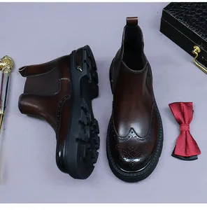 Close-up of brown leather Chelsea boots with brogue carving and durable rubber soles