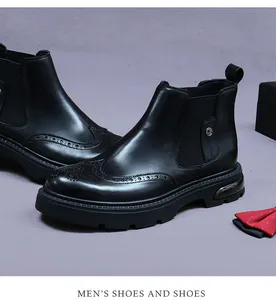 Close-up of black leather Chelsea boots with brogue wingtip detailing and thick sole