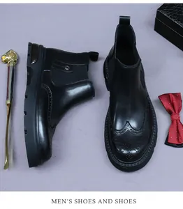 Detail view of black leather Chelsea boots with brogue carving and premium finish