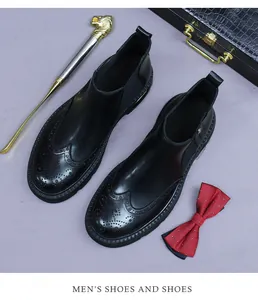 Classic black leather Chelsea boots with brogue wingtip detailing for men on desk
