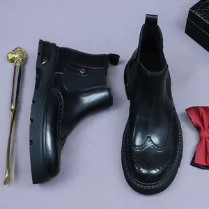 Polished black leather Chelsea boots with brogue carving details and thick soles