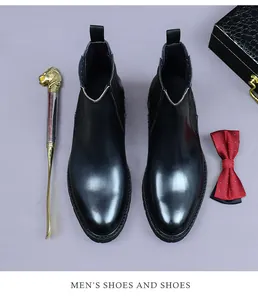 Overhead view of black leather Chelsea boots with elastic sides and golden shoehorn