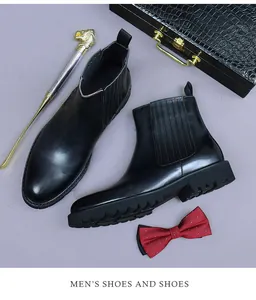 Close-up of black leather Chelsea boots with thick lug sole, shoehorn and bowtie set