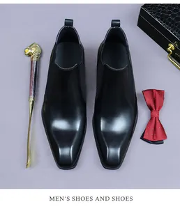 Vue à plat de bottines Chelsea en cuir noir avec bout carré et accessoires élégants