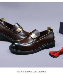 Detail of dark brown leather loafers with gold buckle and gradient burnished toe cap