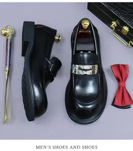 Top view of black leather loafers with metal buckle beside a shoehorn and bow tie