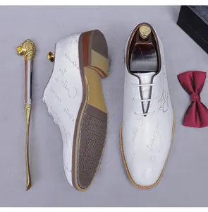 Detail view of white leather derby shoes with script print, brown sole and lion shoehorn