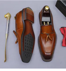Detailweergave van bruine leren loafers met kwastjes, stiksels en metalen schoenlepel