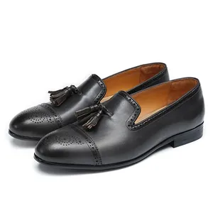 Mocasines clásicos de cuero negro con borlas y detalles Brogue mostrados en un ángulo de 45 grados