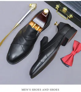 Formal black leather loafers paired with luxury accessories on a textured background