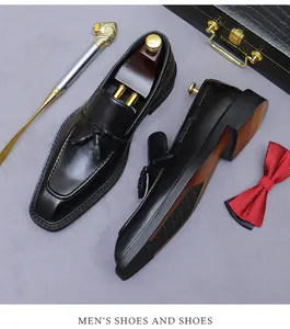 Detail van zwarte lederen loafers met kwastjes en houten schoenspanners op achtergrond