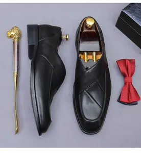 Detail of matte black leather loafers with gold lion shoe horn and red polka dot bowtie