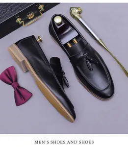 Flat lay of black leather loafers with tassels, lion shoehorn, and briefcase