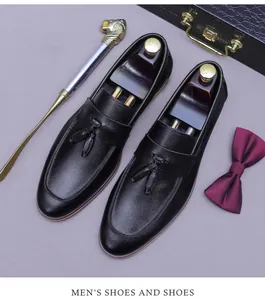 Close-up of black leather tassel loafers with a wooden shoe tree and luxury accessories