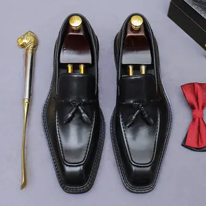 Klassieke zwarte leren herenloafers met kwastjes gepresenteerd met houten schoenspanners