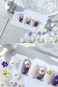 Detailed macro view of 5D daisy and purple smiley face embossed nail art decals