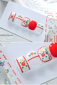 Detailed close-up of matte red and floral nail stickers with gold dot patterns