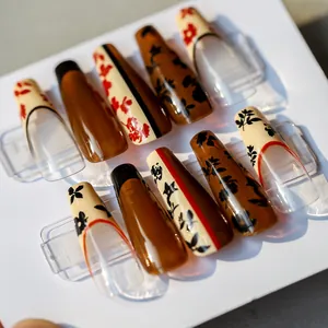 Floral pattern press-on nails with amber base and long coffin shape on display card