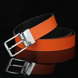 Detail of orange leather belt with silver rotating pin buckle on reflective black surface