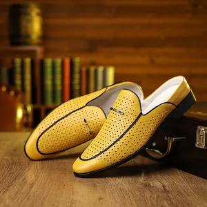 Detail of yellow perforated leather loafers featuring gold metal buckle on a desk