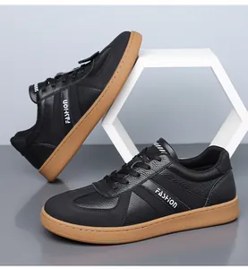 Detail van zwarte lederen herensneakers met bruine gomzool en modieuze tekstbelettering